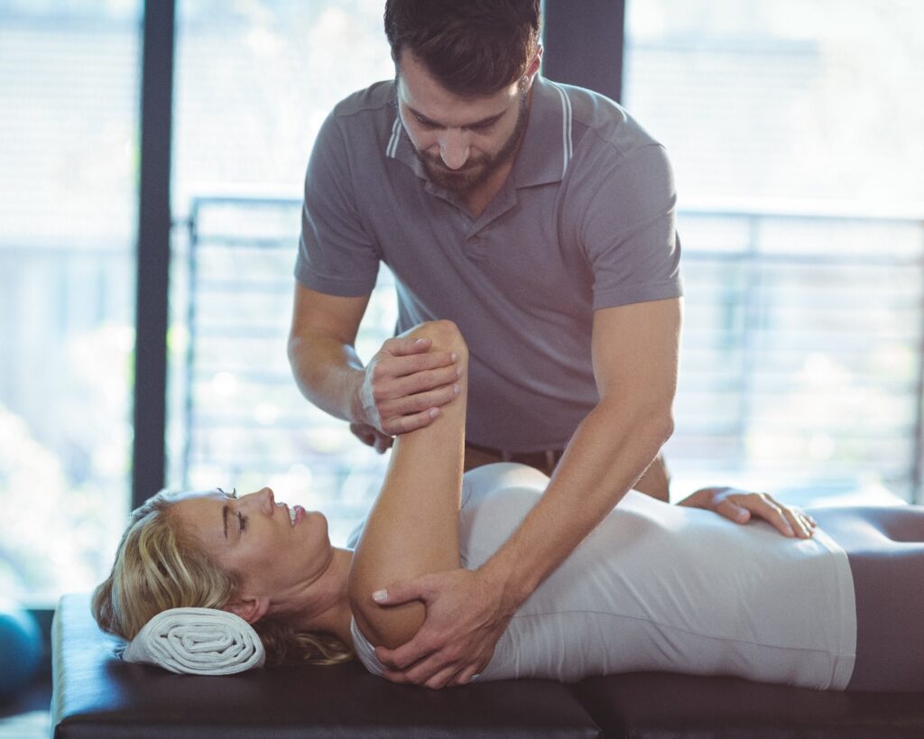 Ein Physiotherapeut behandelt eine Frau an der Schulter